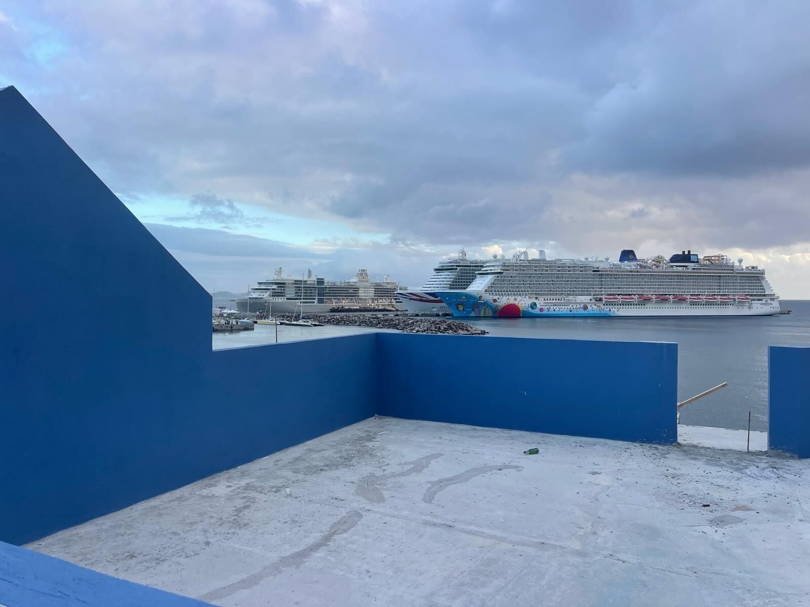 Un gran crucero amarrado en un puerto, con una estructura azul al frente.