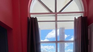 A window with curtains, a tiled floor, and a view of the sea and clouds. - The Colosseum (Basseterre)