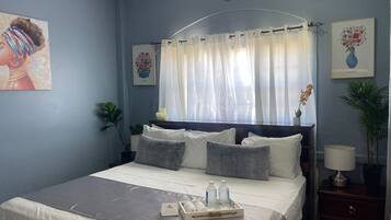 Un dormitorio con cama, mesitas de noche, un reloj y obras de arte en las paredes.