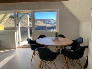 Relax in this serene room with a round table, six chairs, and a potted plant, offering a view of the surrounding landscape.