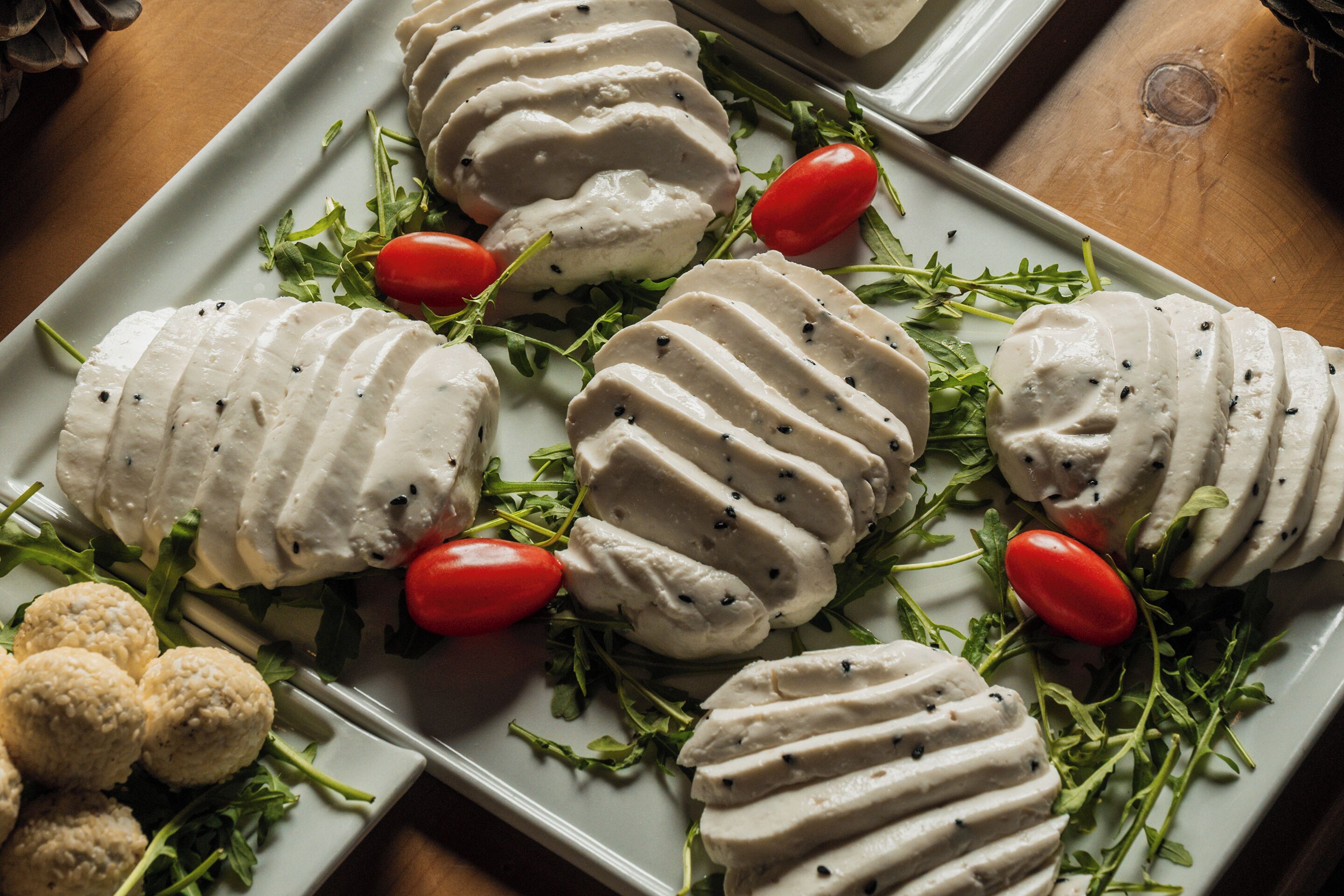 A plate of sliced mozzarella cheese garnished with cherry tomatoes and arugula.