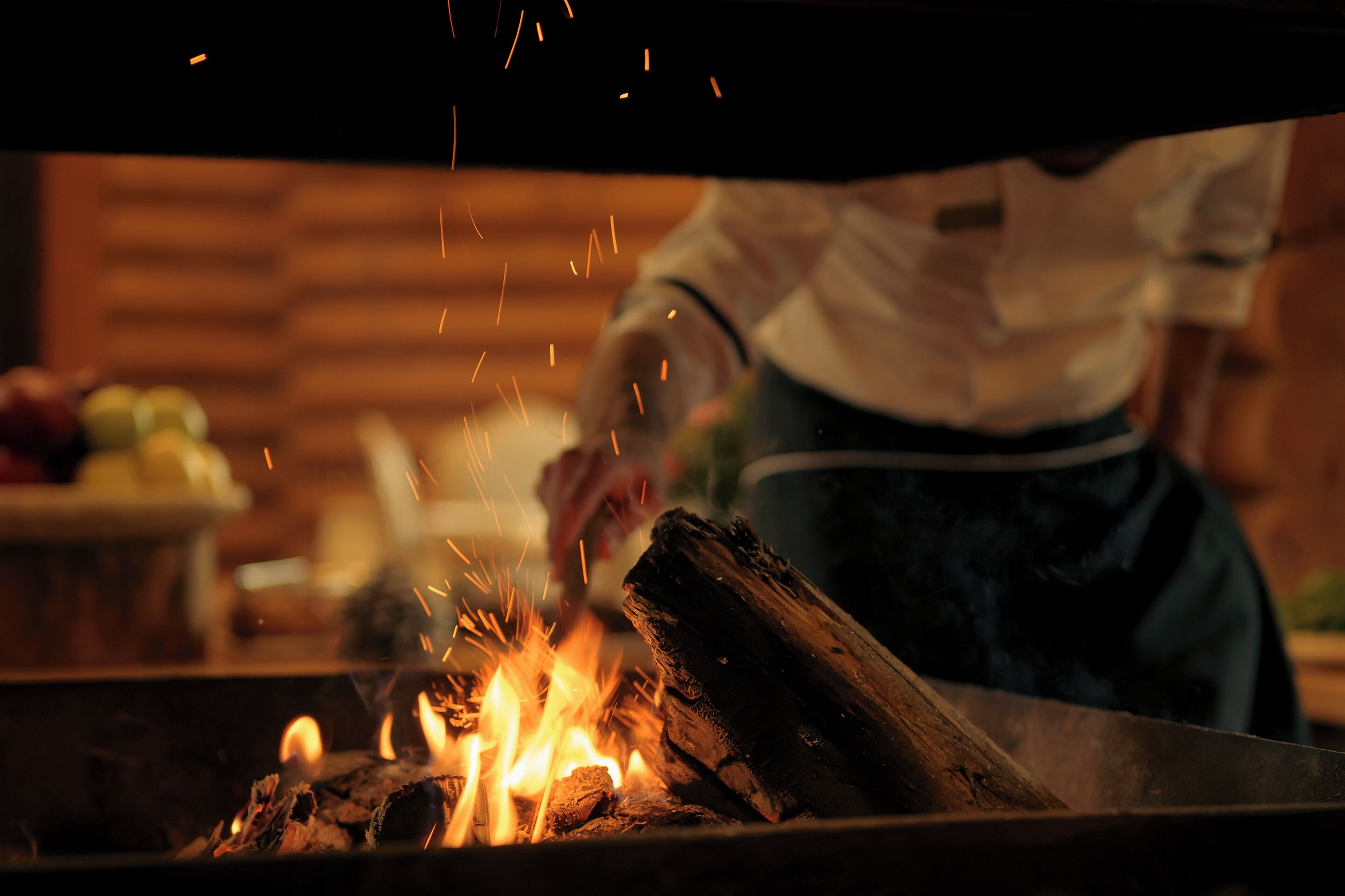 A chef cooking with a wood fire, with sparks flying.