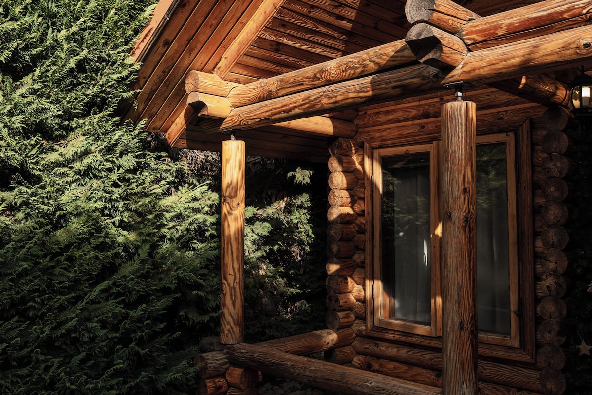 A log cabin with a wooden exterior, a window, and a porch area.