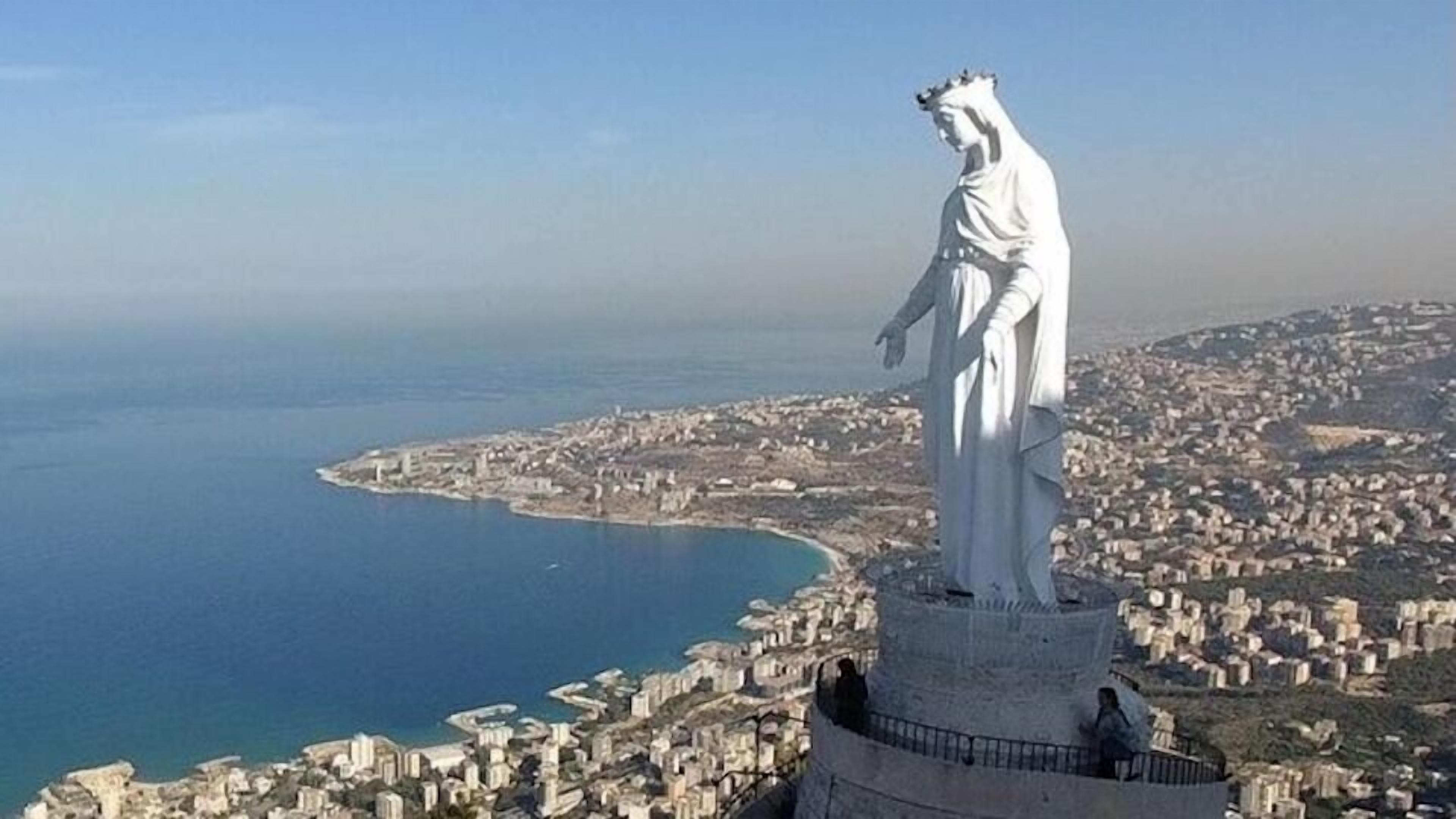 A statue overlooking a coastal cityscape.