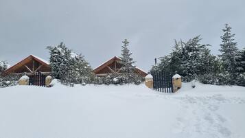 A snow-covered lodge with wooden cabins, a snow-covered fence, and trees.