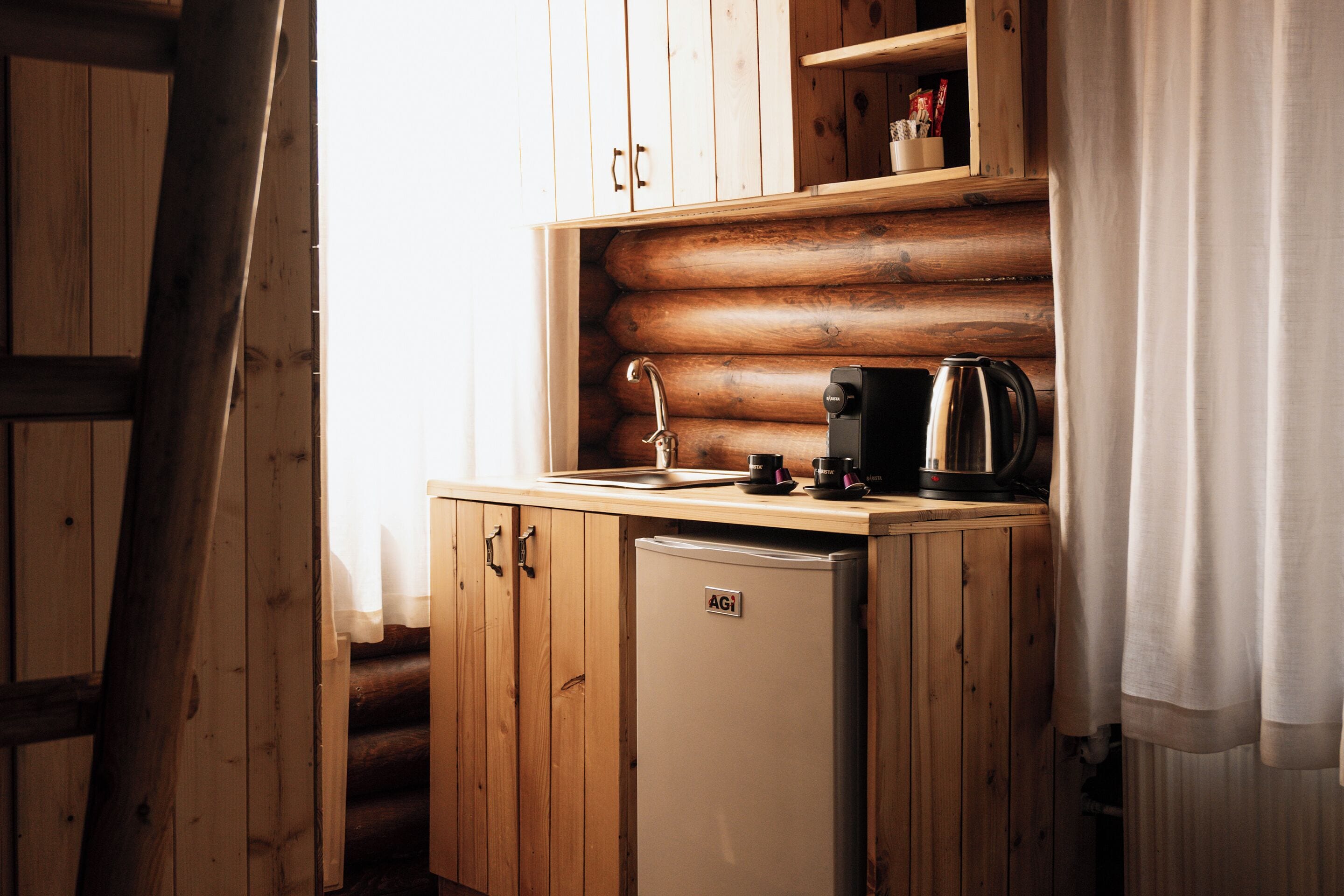 A compact kitchen with wooden cabinets, a refrigerator, and a coffee maker.