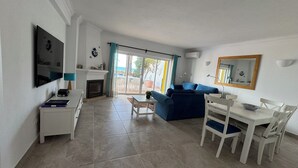 Una sala de estar con televisión, chimenea, sofá, mesa de comedor y sillas.