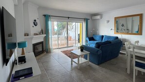 Una sala de estar con un sofá, una mesa de centro, un televisor y una chimenea.