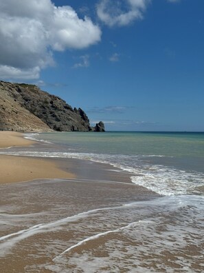 A beach with clear skies, a rocky cliff, and calm waves. - 22D seafront apartment with pool (Luz, Faro)