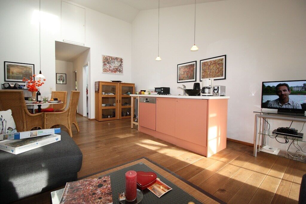 A modern living room with a sofa, dining area, kitchen, and a TV.