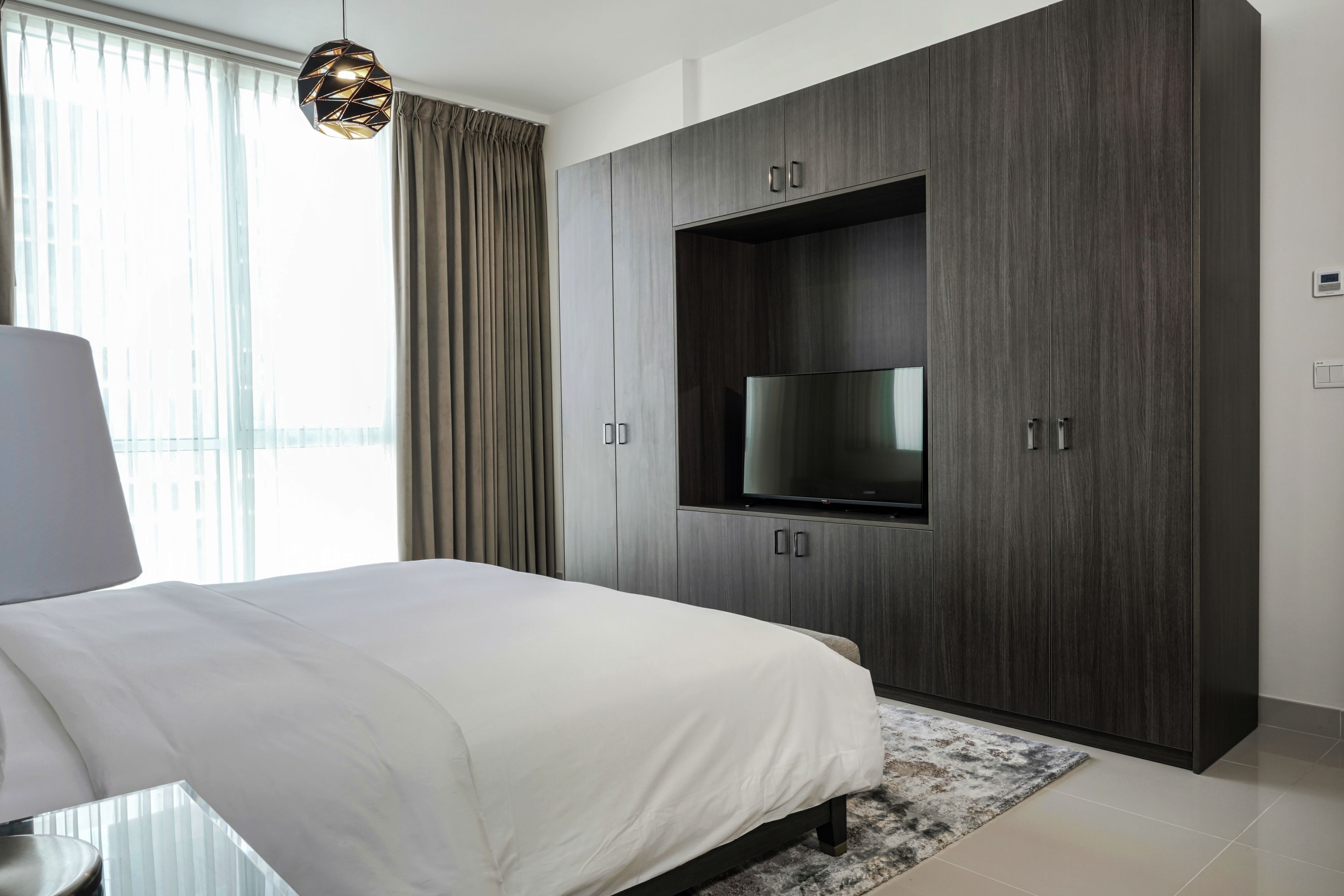 A modern bedroom with a large bed, a built-in TV, and a wardrobe with cabinets.