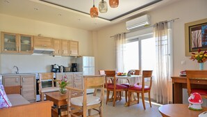 A modern kitchen with wooden cabinets, a dining area with red chairs, and a small table with a vase of flowers. - Olive Garden house (Καμηλάρι)