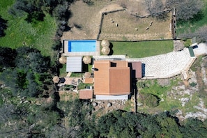 Eine Vogelperspektive eines Grundstücks mit Swimmingpool, überdachter Terrasse und umzäunter Garten.