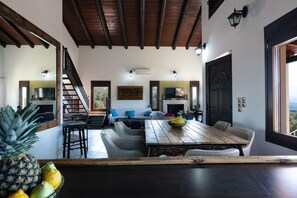 A spacious living area with a wooden dining table, a sofa set, and a fireplace.