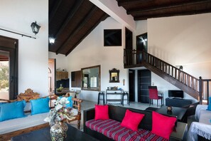 A spacious living area with a high ceiling, a staircase, and a dining area.