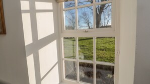 A room with a large window overlooking a grassy area.