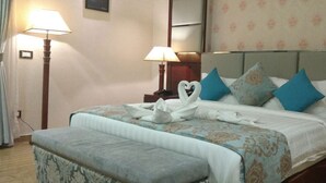 Une chambre d’hôtel avec un lit, deux lampes de chevet et un papier peint à motifs floraux.