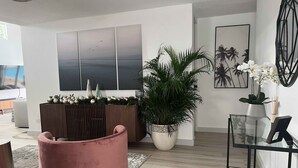 A modern living room with a large TV, a pink chair, a potted plant, and a glass coffee table. - Luxury 5 Bedroom Home, 3 Minute Walk from the Beach (Dorado)