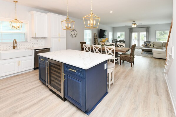 A modern kitchen with a large island, white cabinets, and blue accents.