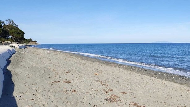 Una playa con arena dorada y un cielo azul despejado.