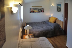 Une petite pièce agréable, dotée d’un lit, d’une table de chevet avec une lampe et d’un tableau accroché au mur.