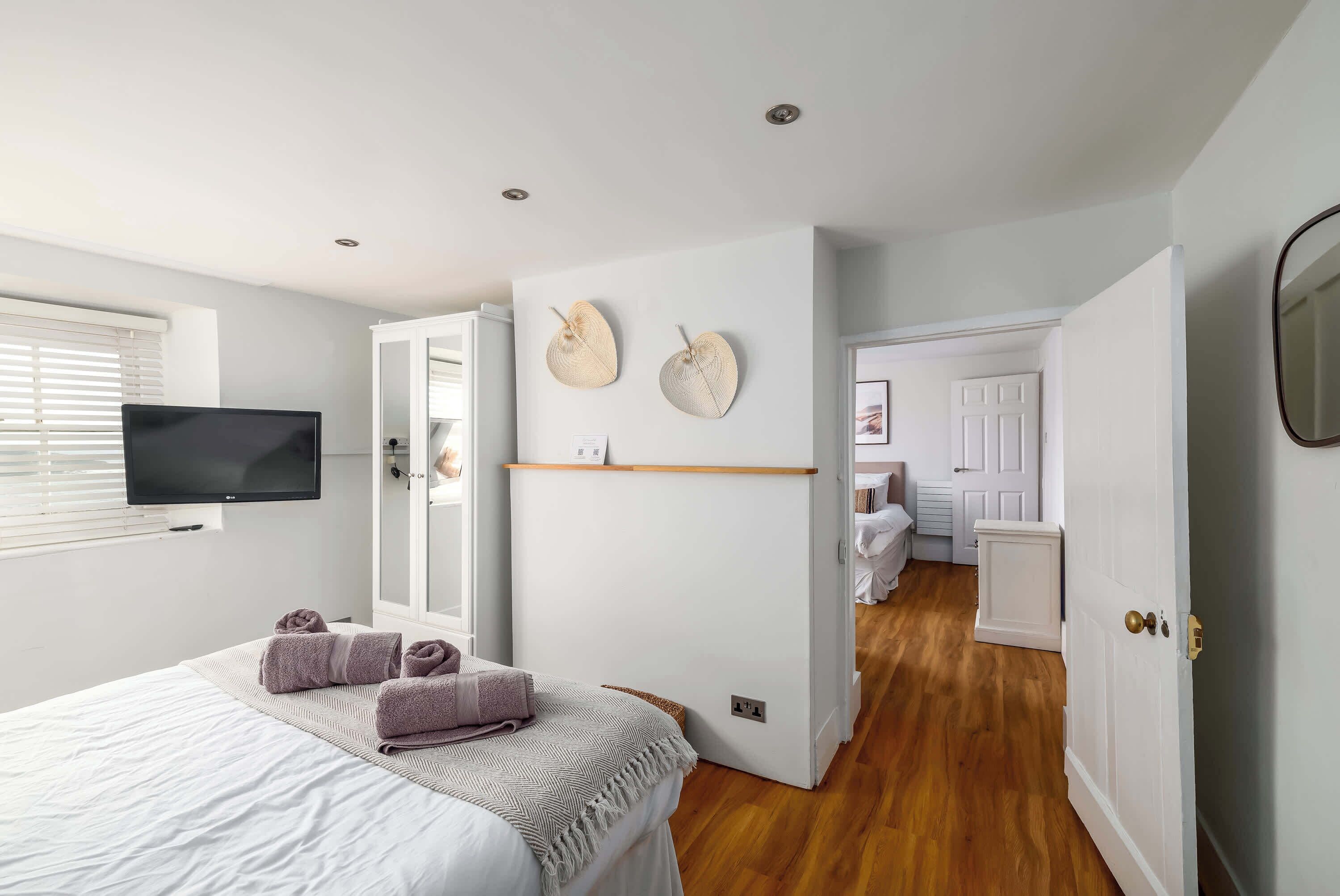 Ein Schlafzimmer mit einem Bett, einem Fernseher und einer Tür zu einem anderen Raum.