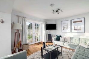 A living room with a sofa, a coffee table, a TV, and a window with curtains.