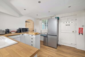 A compact kitchen with a wooden countertop, a stainless steel refrigerator, and a dishwasher. - NEW 2023 Beach House in Devon - Sleeps 10 (Bovisand)
