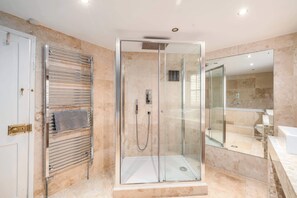A modern bathroom with a glass-enclosed shower, a towel rack, and a large mirror.