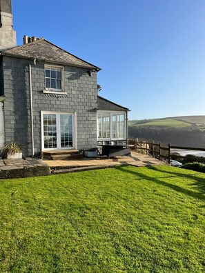 A two-story house with a stone facade, large windows, and a grassy yard.