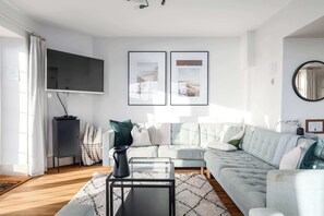 A modern living room with a grey sofa, a flat-screen TV, and two framed pictures on the wall. - NEW 2023 Beach House in Devon - Sleeps 10 (Bovisand)