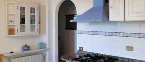 Une cuisine avec des meubles blancs, un dosseret carrelé et une cuisinière.