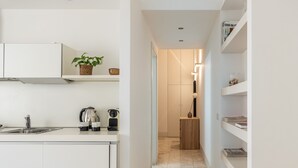 A narrow hallway with a kitchen area on one side, featuring a sink, kettle, and cabinets. - Torremuzza Home by Wonderful Italy (Palermo)