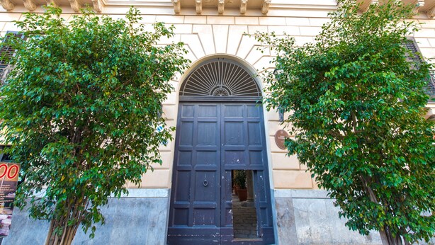A building facade with a large central door, two balconies with wrought iron railings, and a stone staircase leading to an entrance. - Torremuzza Home by Wonderful Italy (Palermo)