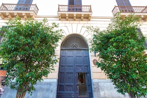 Traditional building with a grand entrance, balcony, and lush surroundings.