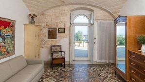 Une pièce avec un mur en pierre, une armoire en bois, un canapé, une chaise et un sol à motifs.