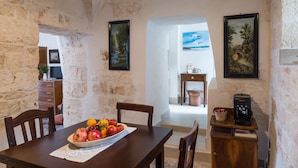 Un coin repas au style rustique, avec un mur en pierre, des meubles en bois et des œuvres d’art.