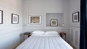 A neatly arranged bedroom with a large bed, two bedside tables, and framed artwork on the walls. - Eleganza nel Cuore di Napoli by Wonderful Italy (Naples)