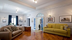 A spacious living room with a wooden herringbone floor, a brown leather sofa, a yellow sofa, and a dining area with a white table and chairs. - Eleganza nel Cuore di Napoli by Wonderful Italy (Naples)