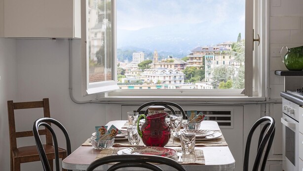 A dining table set for four with a view of a cityscape through a window. - Appartamento a Villa Montuoro by Wonderful Italy (Rapallo)