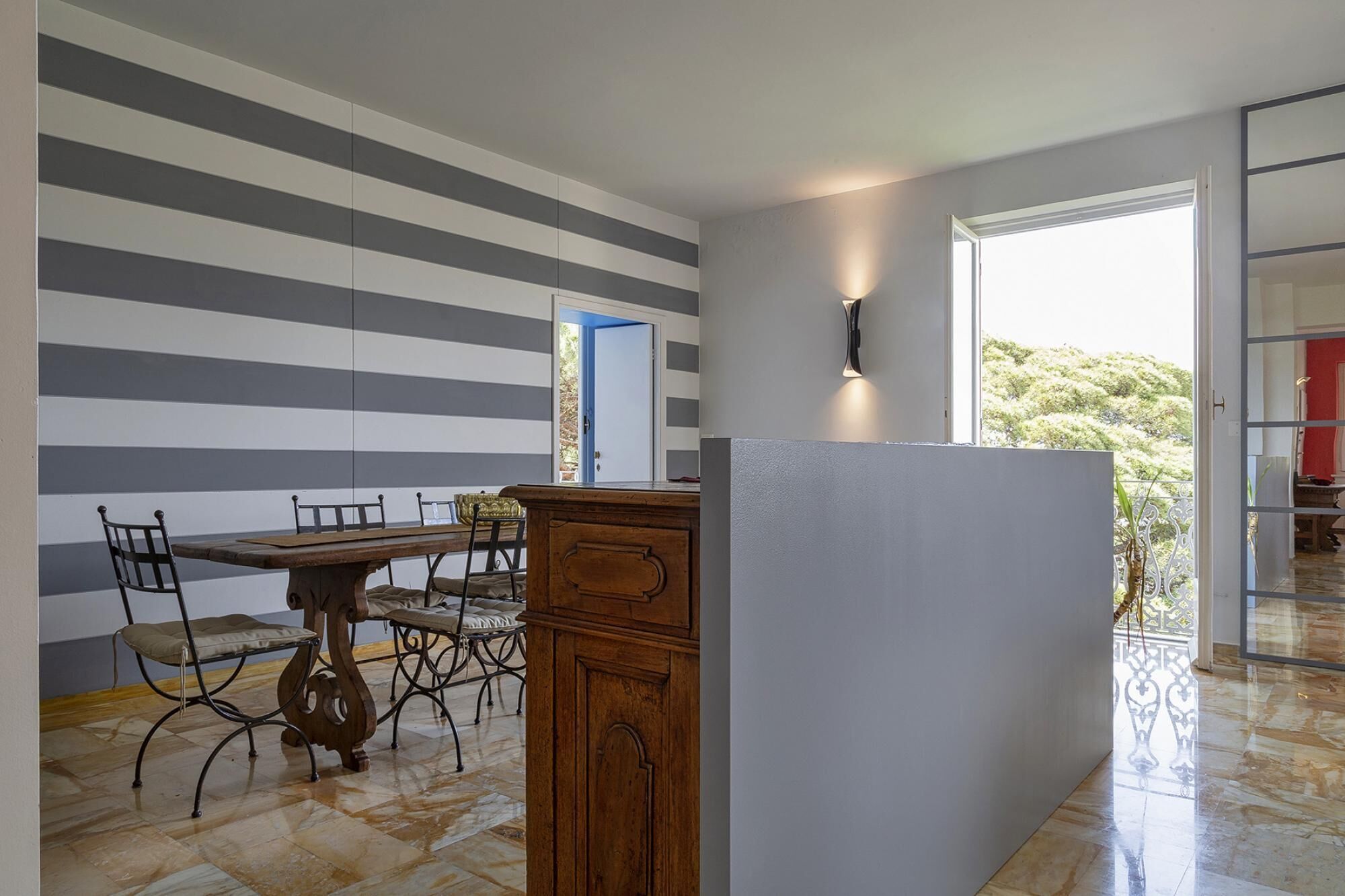 A modern kitchen with striped walls, a wooden dining table, and a built-in refrigerator.