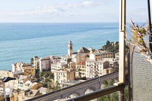 Un pueblo costero con edificios históricos, una torre destacada y un puente que conduce al mar.