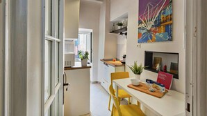 Una cocina moderna con armarios blancos, encimera de madera y una zona de comedor con sillas amarillas.