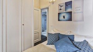 Un dormitorio con cama, almohadas y decoración de paredes que representa escenas marinas.