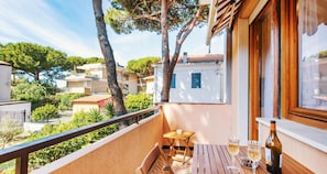 Un balcon avec une table et des chaises, une bouteille de vin et un verre de vin.