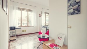 A hotel room with a bed, a desk, a chair, a lamp, a window with curtains, a clock, and a calendar on the wall. - Sanremo Central Nest by Wonderful Italy (Sanremo)