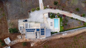 An aerial view of a modern house with a swimming pool, solar panels, and a well-maintained garden.