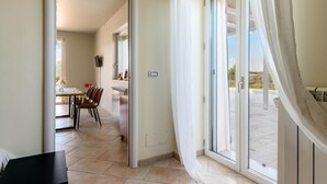 A modern interior with a dining area, a kitchen, and a sliding glass door leading to an outdoor patio.