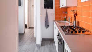 Eine moderne Küche mit weißen Schränken, einer orangefarbenen Spritzschutzwand und einer Edelstahl-Dunstabzugshaube.