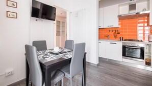 Eine moderne Küche mit weißen Schränken, einer orangefarbenen Spritzschutzleiste und einem eingebauten Backofen.